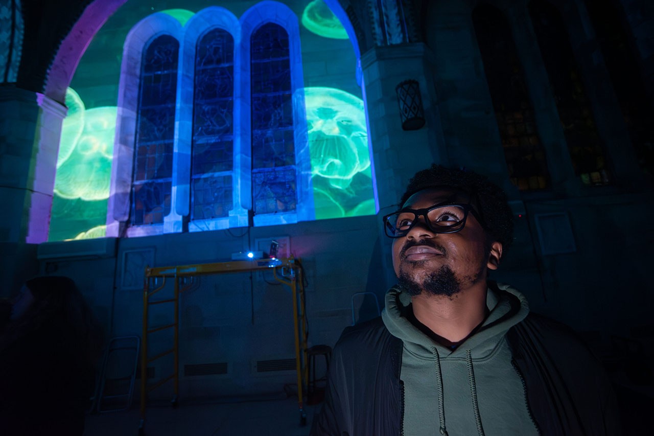 Student Elijah Jones with projection mapping on window in background